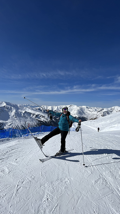 Barbara Clinical Operations Leader at Parexel, standing on ski, smiling at camera, with snowy mountains around her